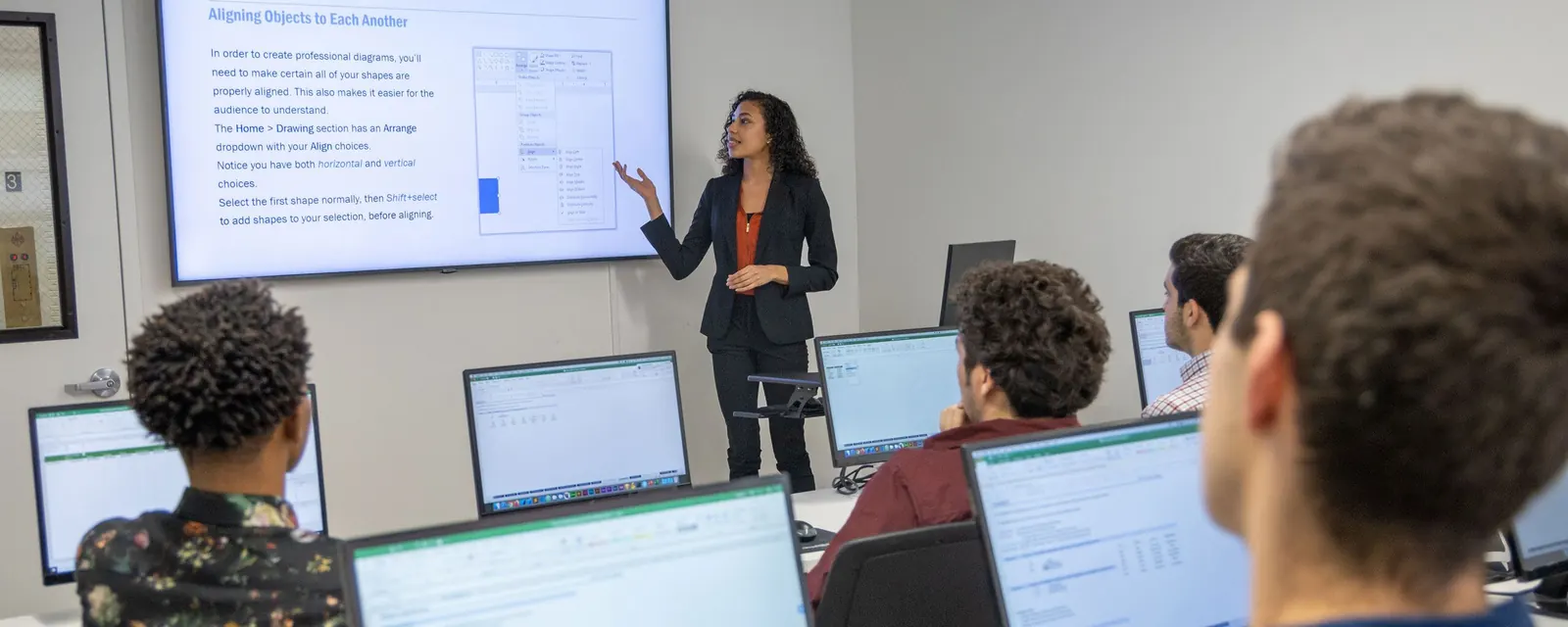 A VDCI instructor working through a drafting exercise with students at workstations
